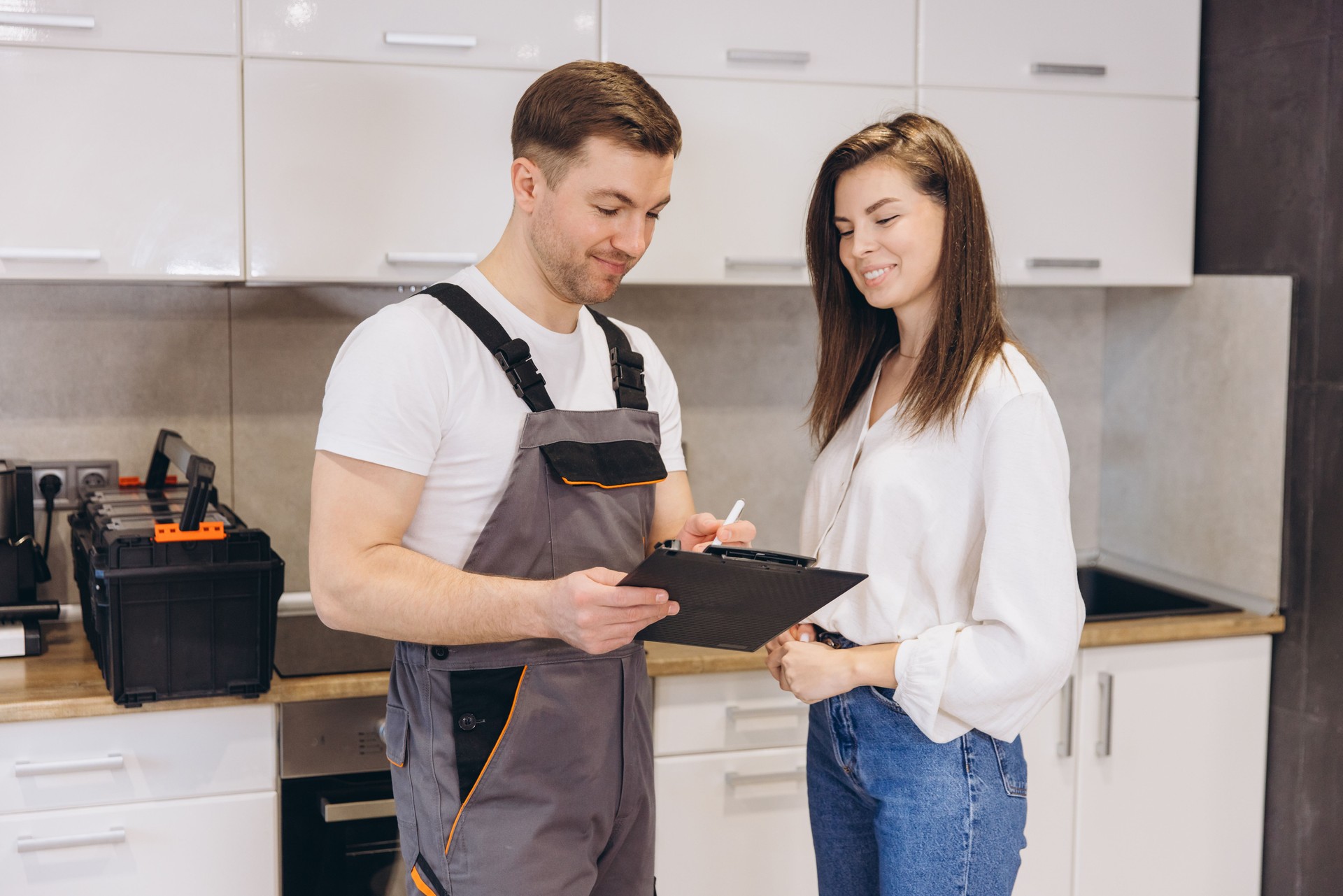 Plumber showing repair cost estimate to woman in kitchen